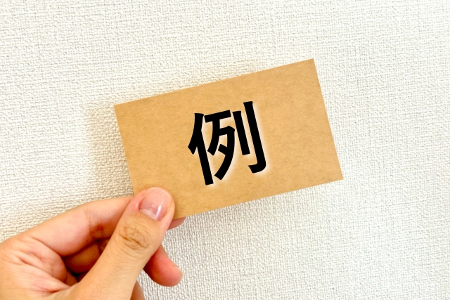 例と書かれた紙を持つ手